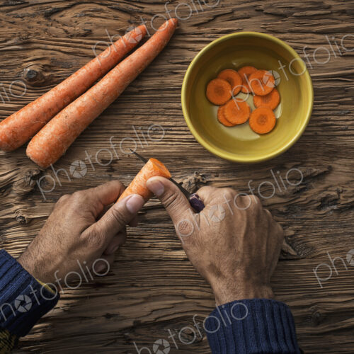 A person holding and slicing fresh carrots into a bowl. A person holding and slicing fresh carrots into a bowl.