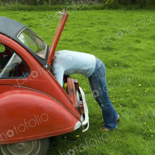 A person leaning in to the boot at the rear of the car. A person leaning in to the boot at the rear of the car.