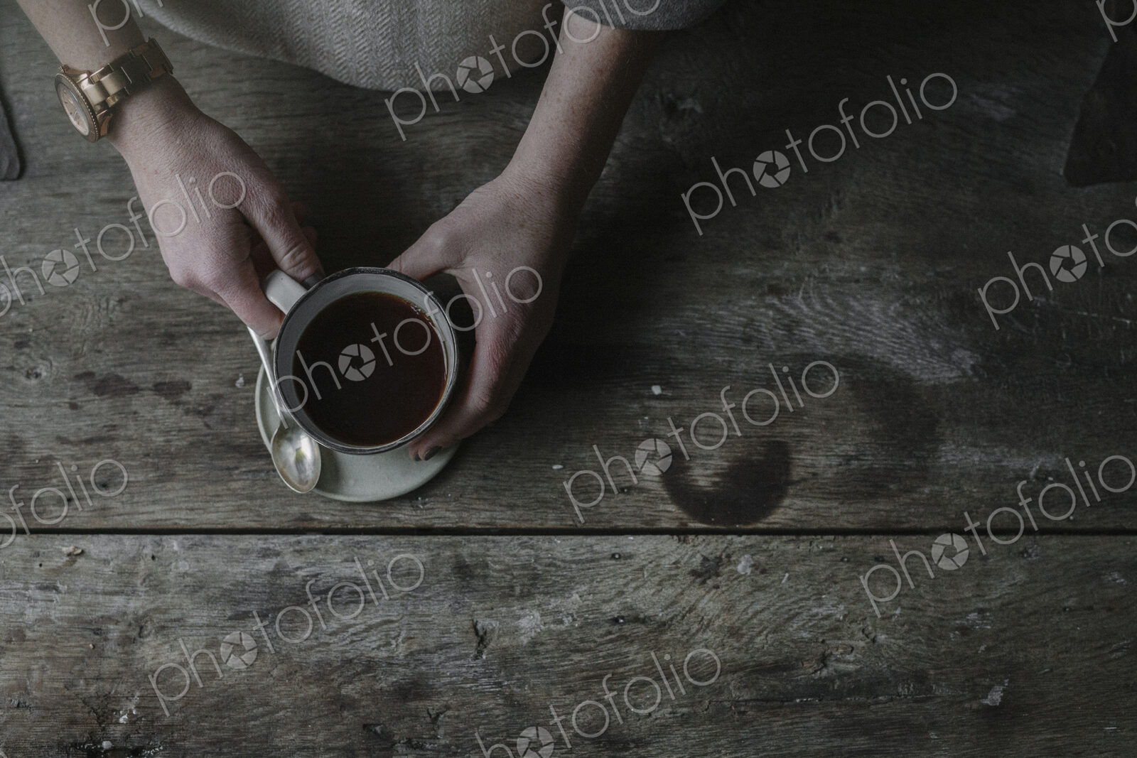 A person lifting a full cup from a saucer.