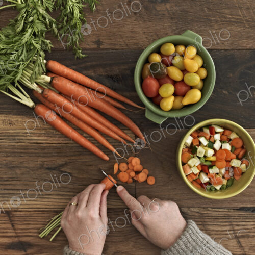 A person preparing fresh vegetables on a wooden table. A person preparing fresh vegetables on a wooden table.