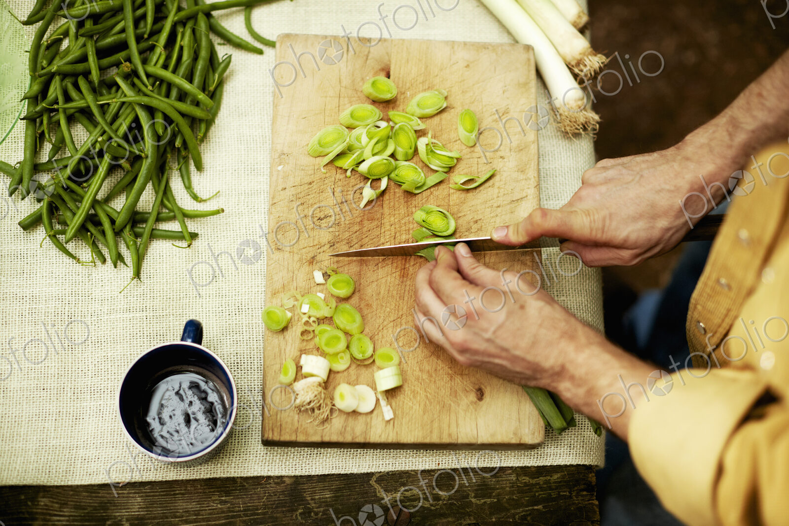 A person preparing vegetables, slicing spring onions on a chopping board.