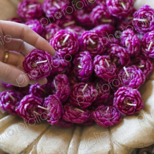 A person selecting a candle from a basket full of purple wax shaped candles. A person selecting a candle from a basket full of purple wax shaped candles.