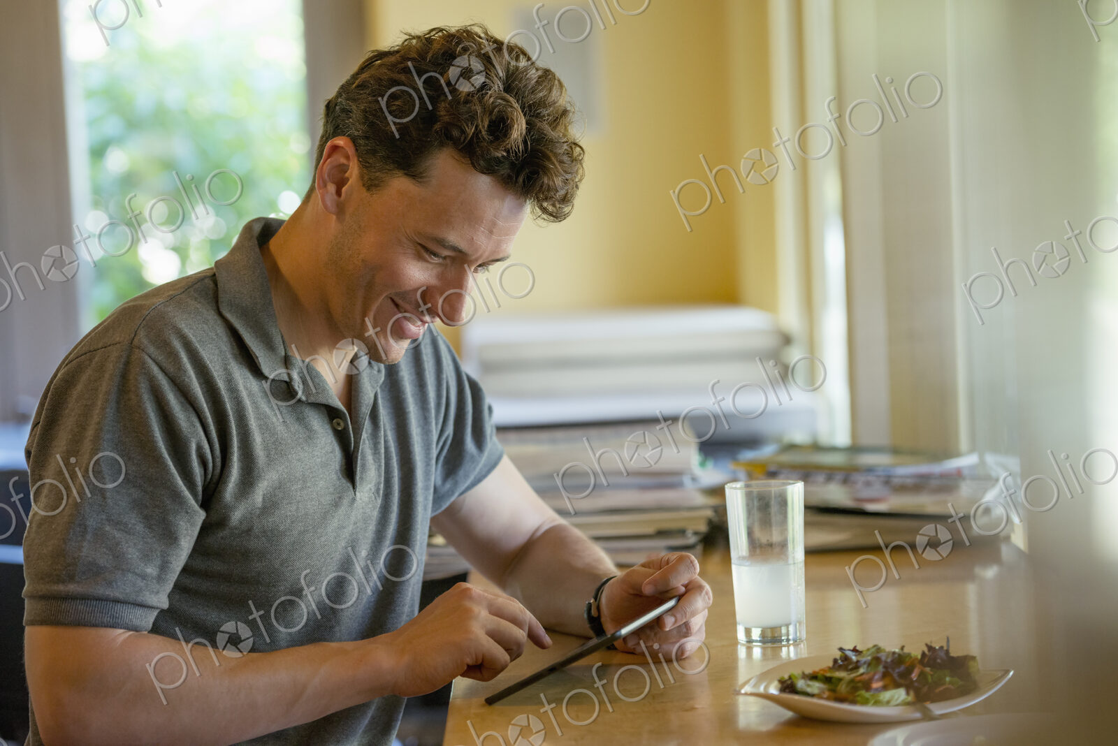 A person sitting alone in a cafe. A man using a digital tablet.