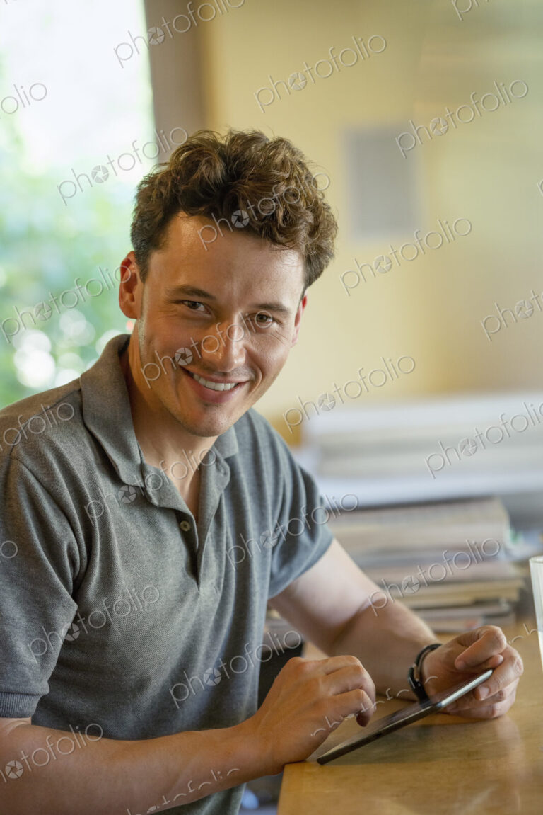 A person sitting alone in a cafe. A man using a digital tablet.