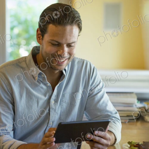 A person sitting alone in a cafe. A man using a digital tablet. A person sitting alone in a cafe. A man using a digital tablet.