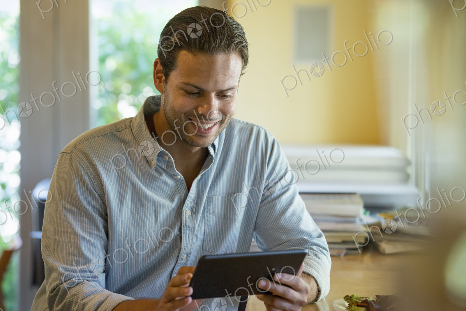A person sitting alone in a cafe. A man using a digital tablet.