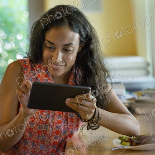 A person sitting alone in a cafe. A woman using a digital tablet.