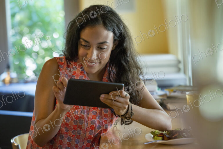 A person sitting alone in a cafe. A woman using a digital tablet.