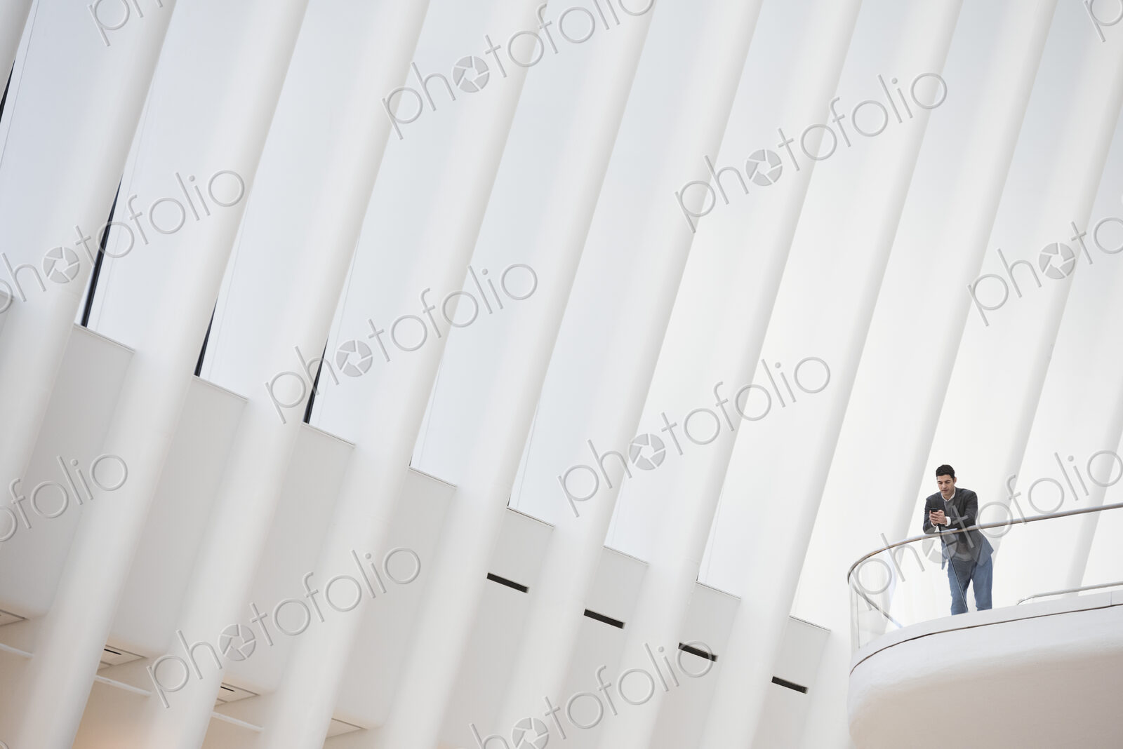 A person standing alone in an atrium by a railing, alone in a large space.