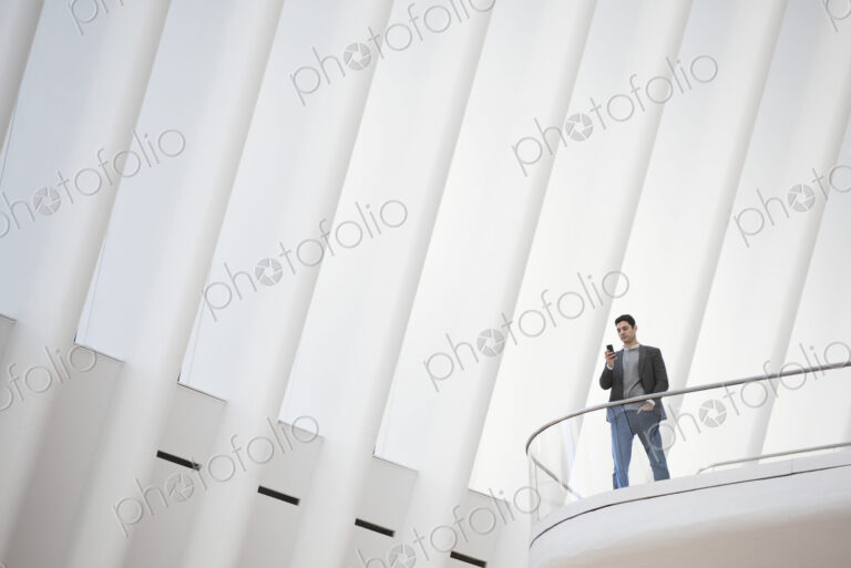 A person standing alone in an atrium by a railing on a balcony.