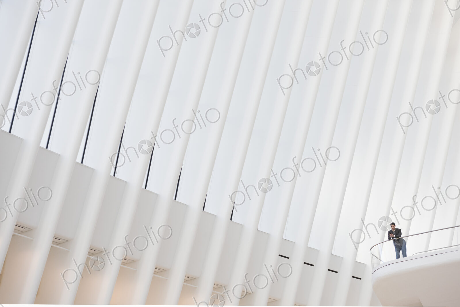 A person standing alone in an atrium by a railing, seen from below