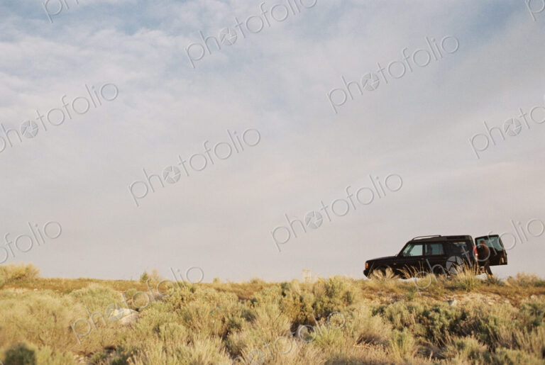 A person standing by the open rear door of a 4x4 vehicle.