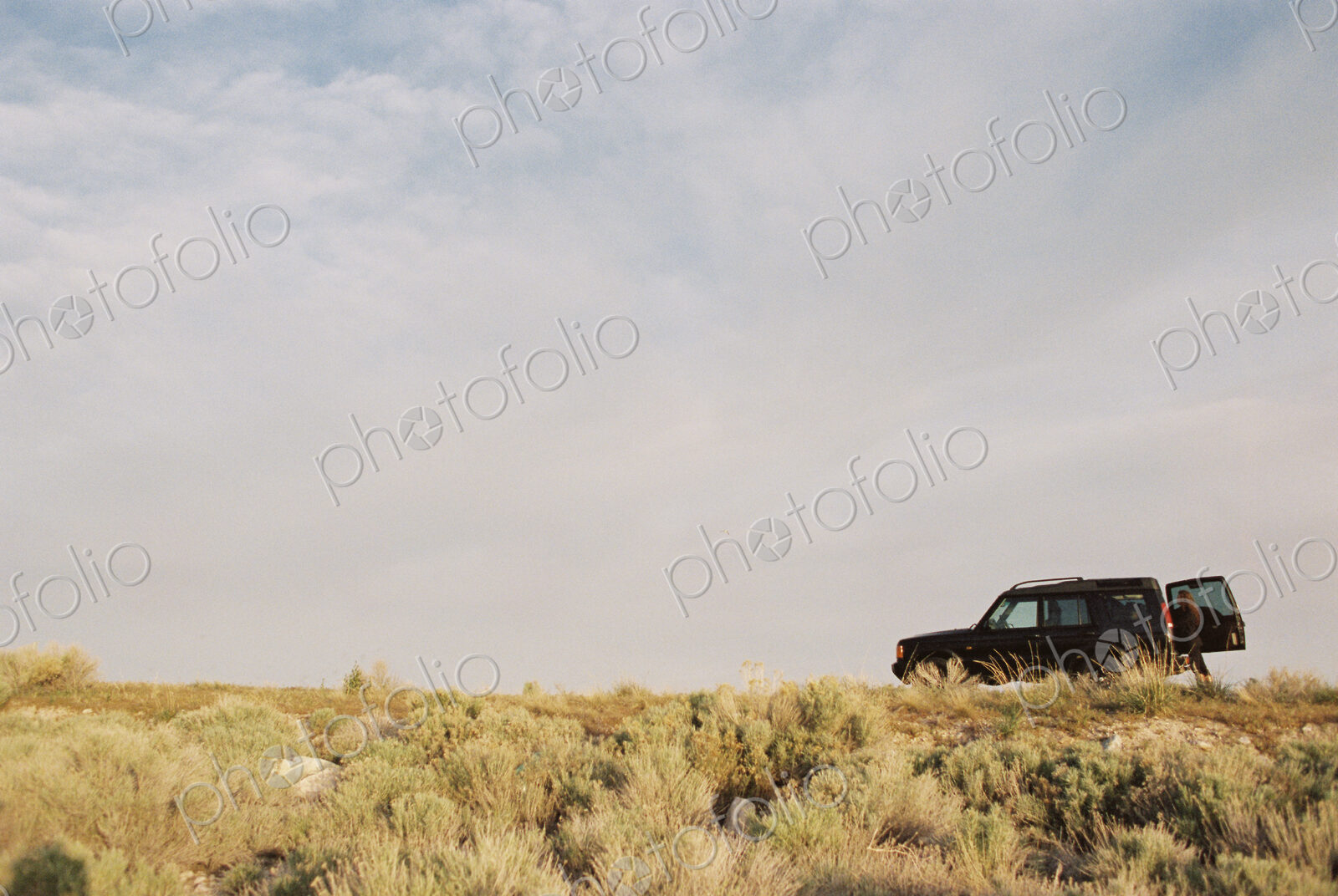 A person standing by the open rear door of a 4×4 vehicle.