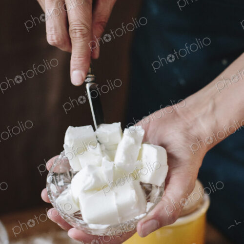 A person using a knife to dice lard for cooking.