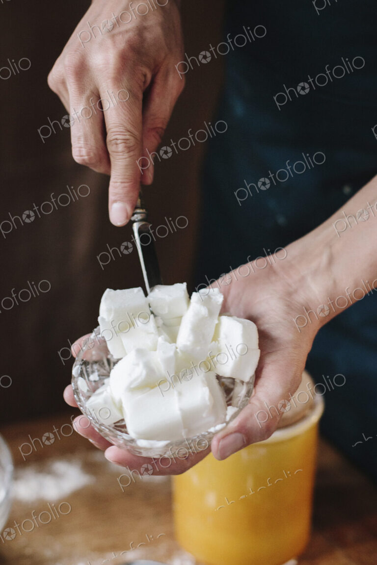 A person using a knife to dice lard for cooking.