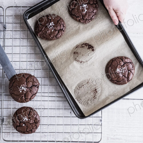 A person using a palette knife to move baked chocolate brownies from a baking tray to… A person using a palette knife to move baked chocolate brownies from a baking tray to…
