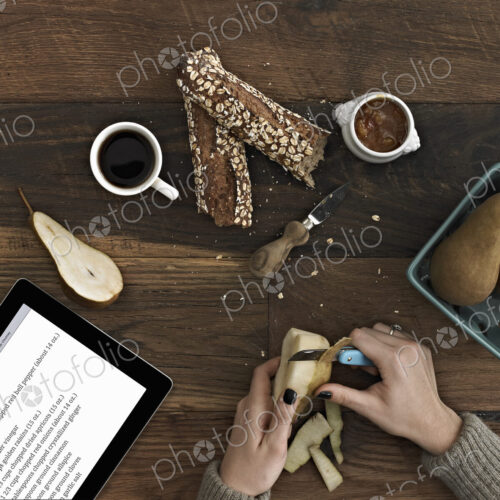 A person using a peeling knife to peel a pear. A computer tablet device with the… A person using a peeling knife to peel a pear. A computer tablet device with the…