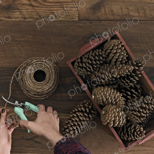 A person using secateurs or cutters on string. A box of pine cones.