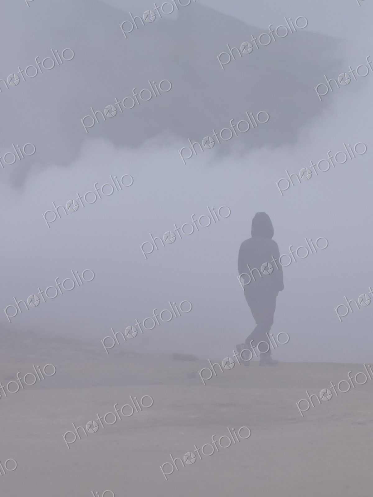 A person walking through the vapour and steam from the hot springs.