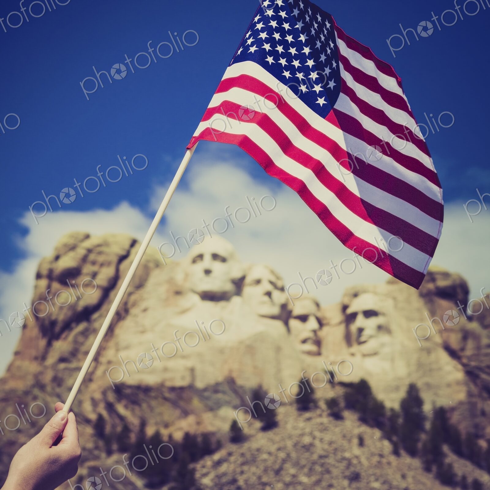 A person waves a United States flag before the granite presidents of Mount Rushmore on…