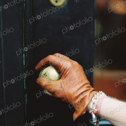 A person wearing a leather glove, opening a door. A person wearing a leather glove, opening a door.