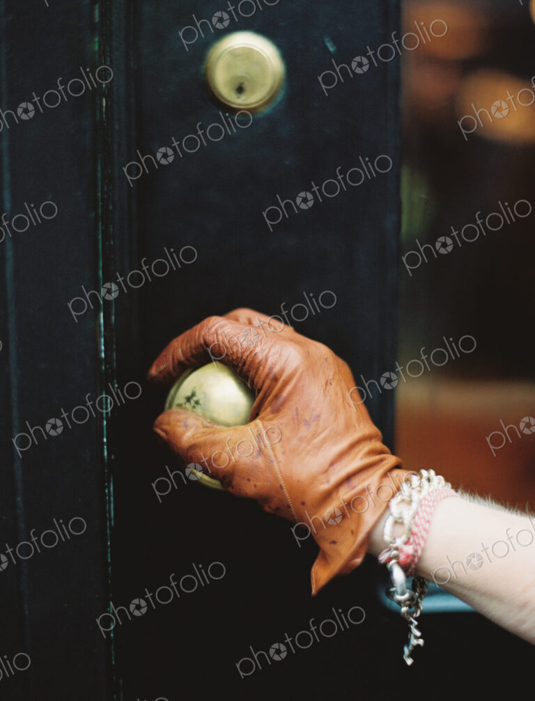A person wearing a leather glove, opening a door.