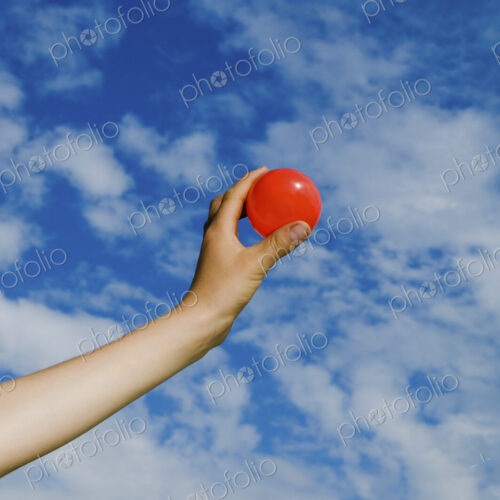 A person's outstretched hand, holding a red ball. A person's outstretched hand, holding a red ball.