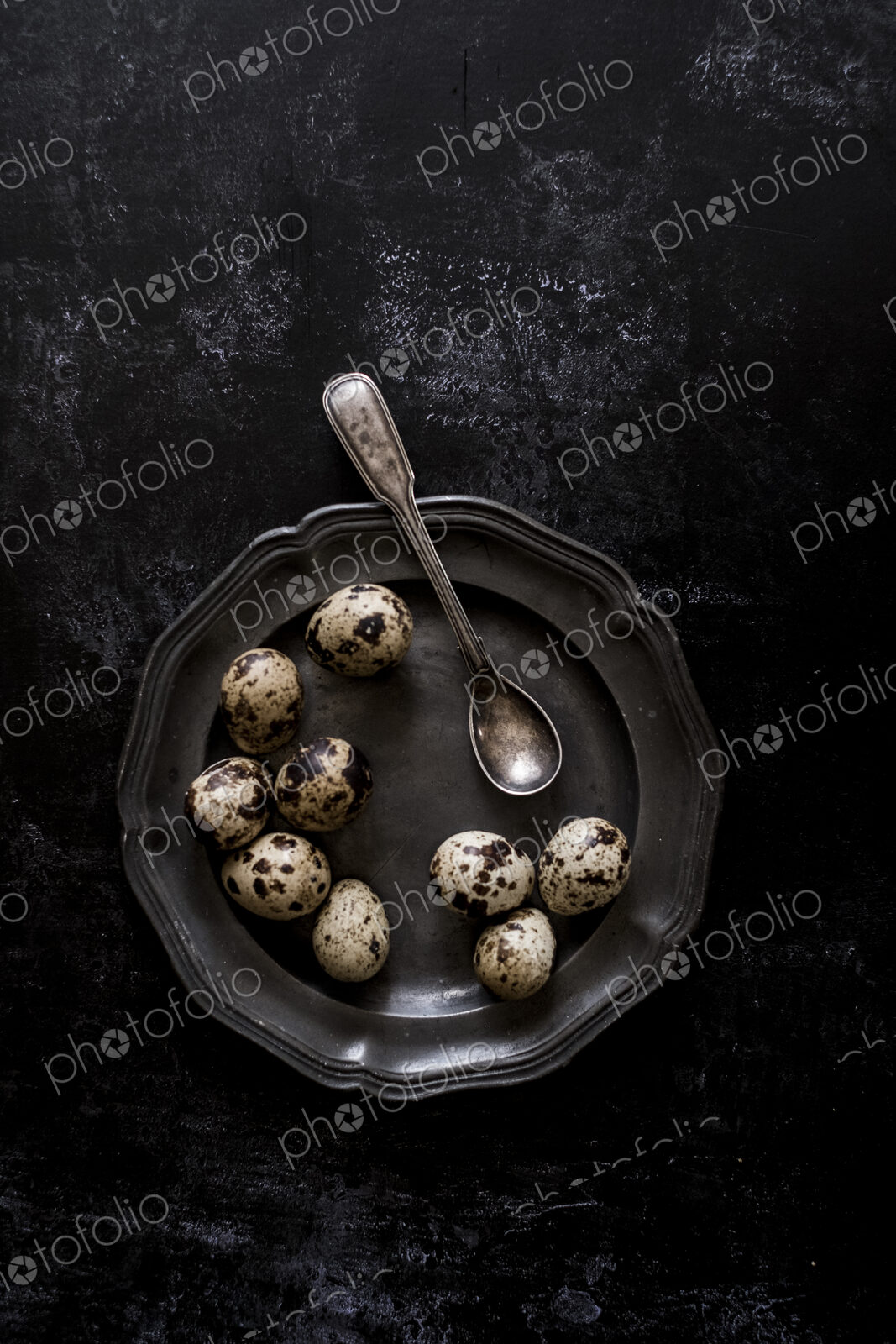 A pewter plate with small spotted quail’s eggs and a spoon.