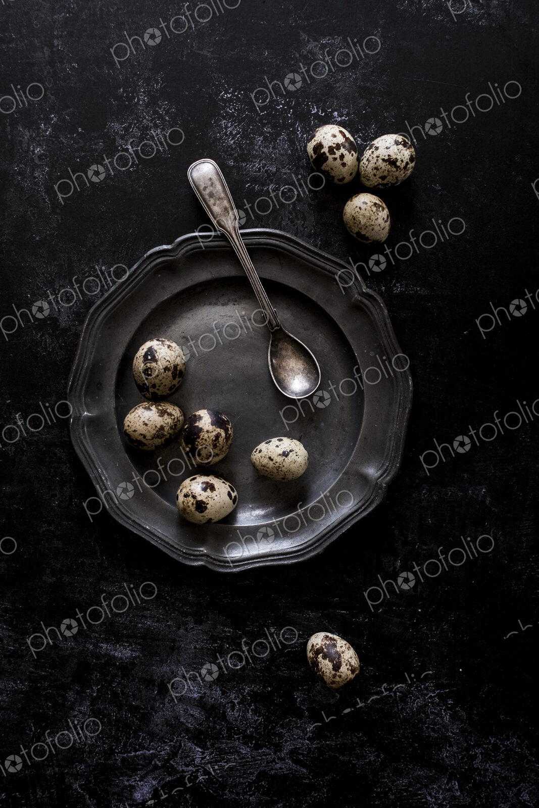A pewter plate with small spotted quail’s eggs and a spoon.