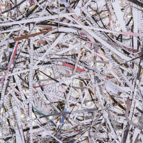 A pile of long thin shredded pieces of printed newspapers.