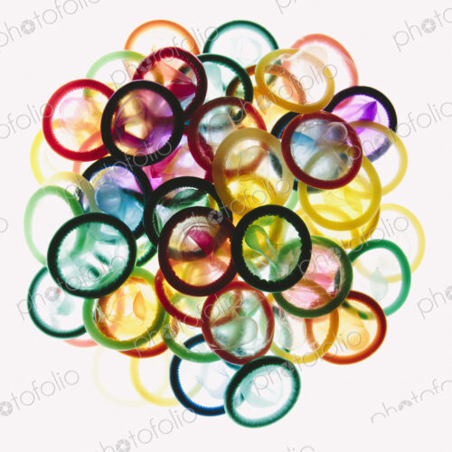 A pile of multi-colored condoms on a white background. A pile of multi-colored condoms on a white background.
