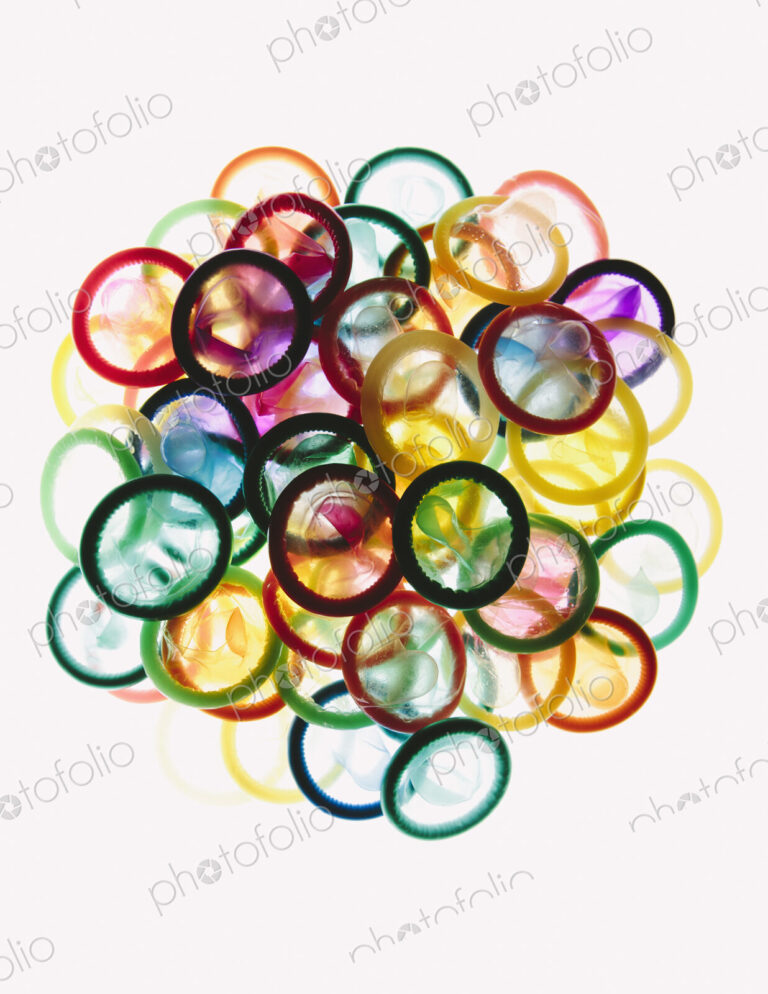 A pile of multi-colored condoms on a white background.