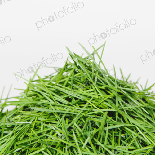 A pile of organic wheatgrass on a white background