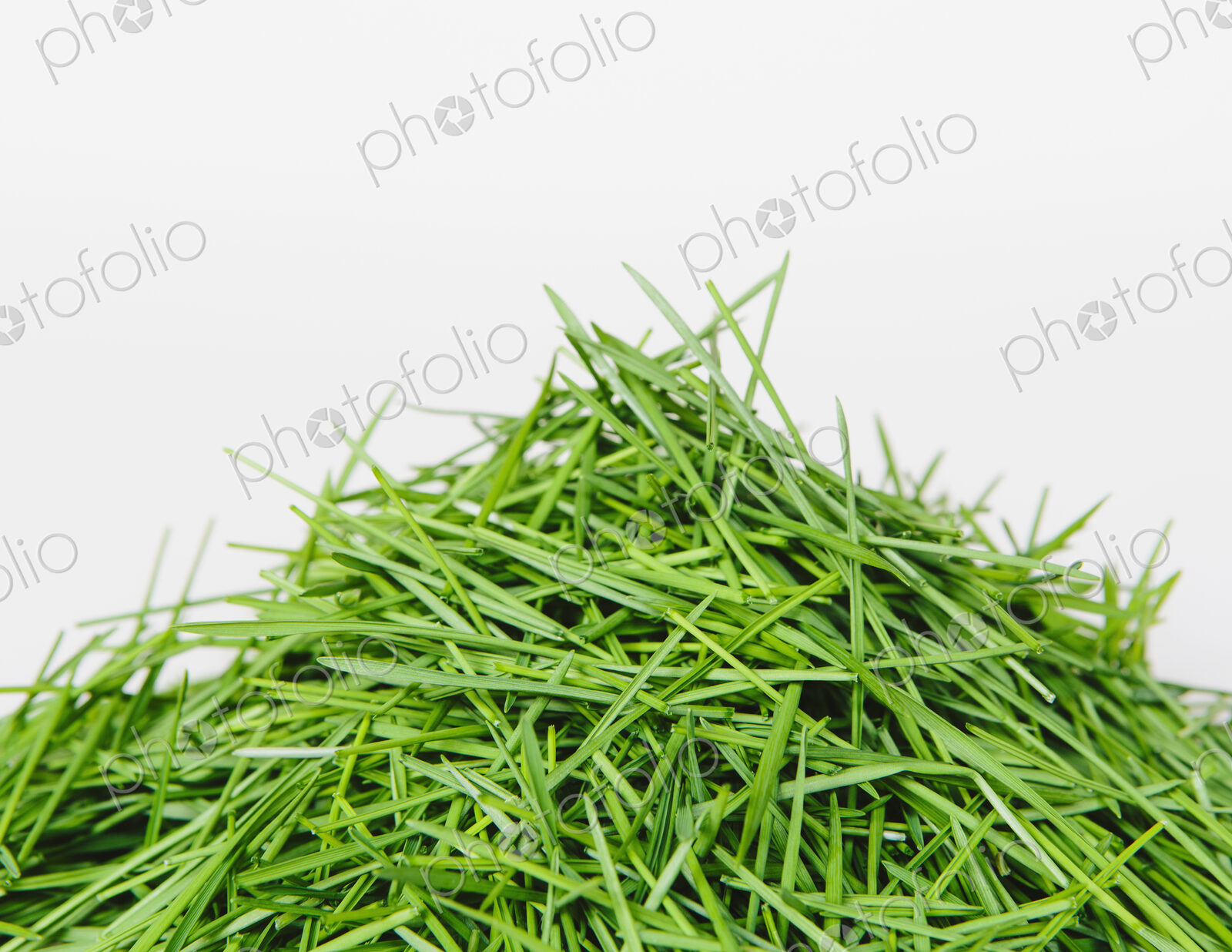 A pile of organic wheatgrass on a white background