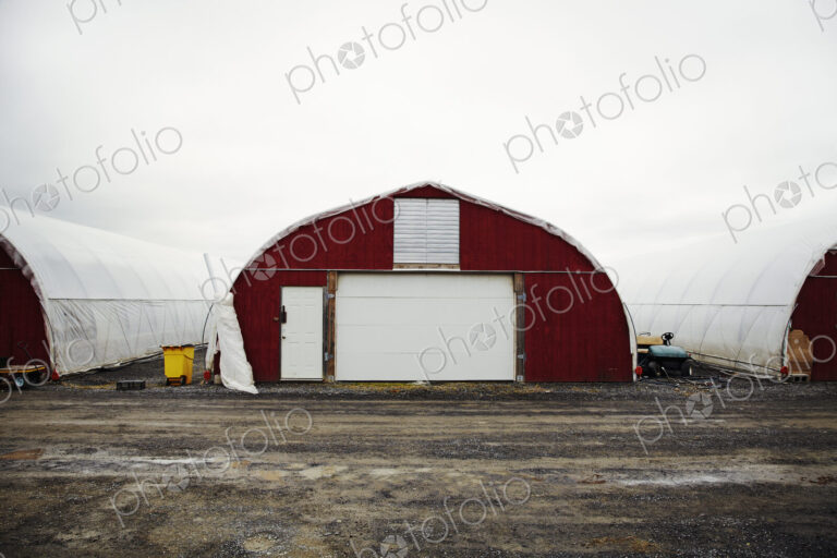 A plant nursery with polytunnels, buildings with ventilation and doors, and white…