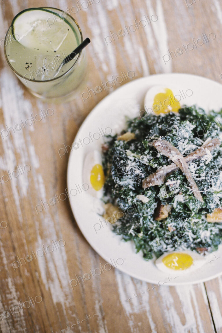 A plate of cooked vegetables and soft boiled eggs, with garnishes.A glass of chilled…