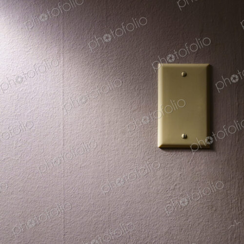 A plate on the wall covering an electrical plug plate in shadow. A plate on the wall covering an electrical plug plate in shadow.