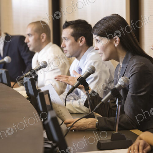 A political meeing with a mixed race group of people at microphones.
