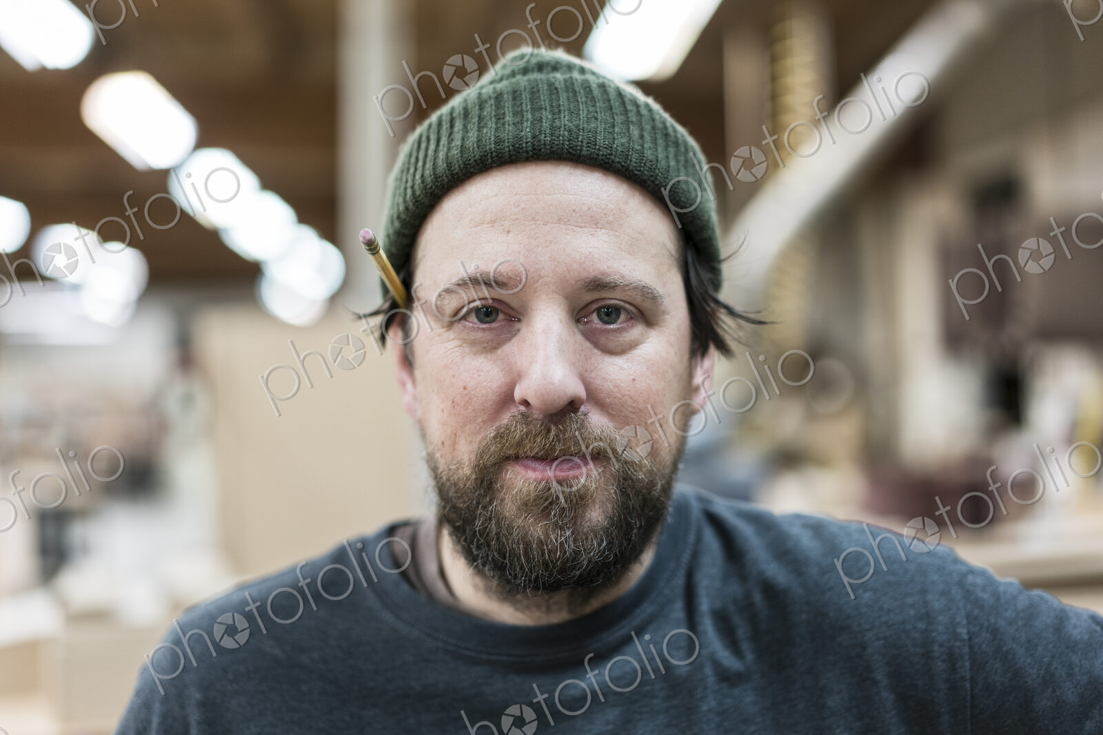 A portrait of a Caucasian carpenter working in a large woodworking shop.