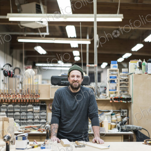 A portrait of a Caucasian carpenter working in a large woodworking shop.