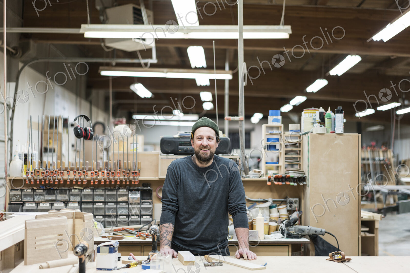 A portrait of a Caucasian carpenter working in a large woodworking shop.
