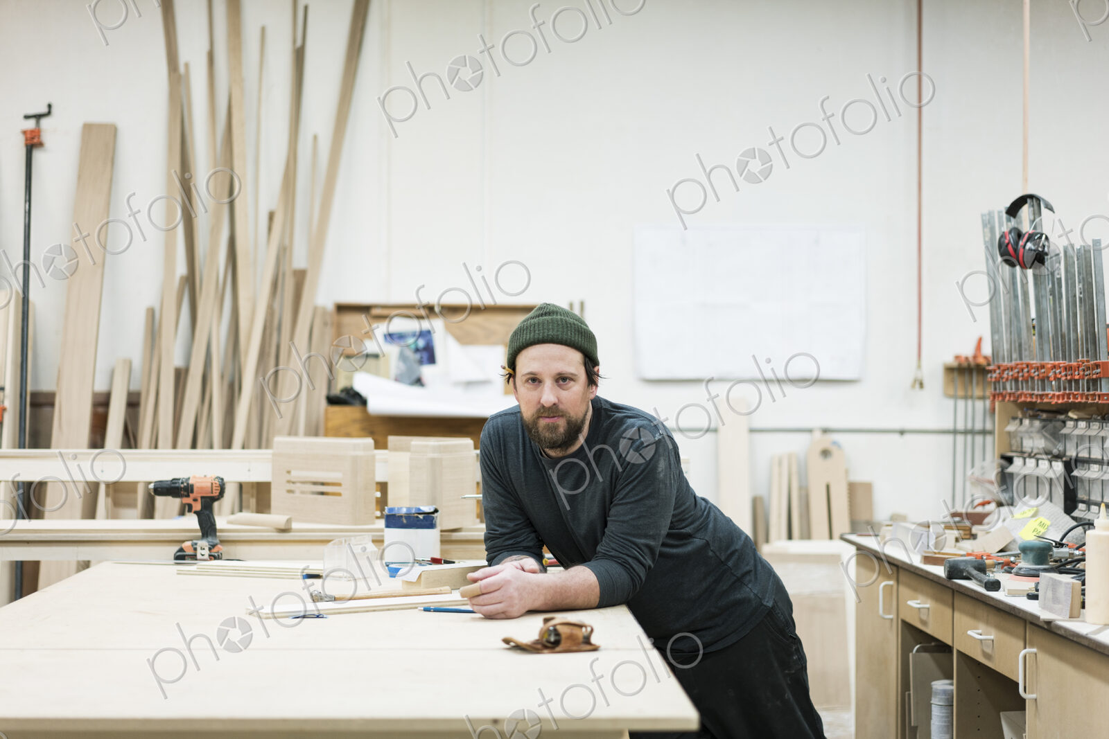 A portrait of a Caucasian carpenter working in a large woodworking shop.