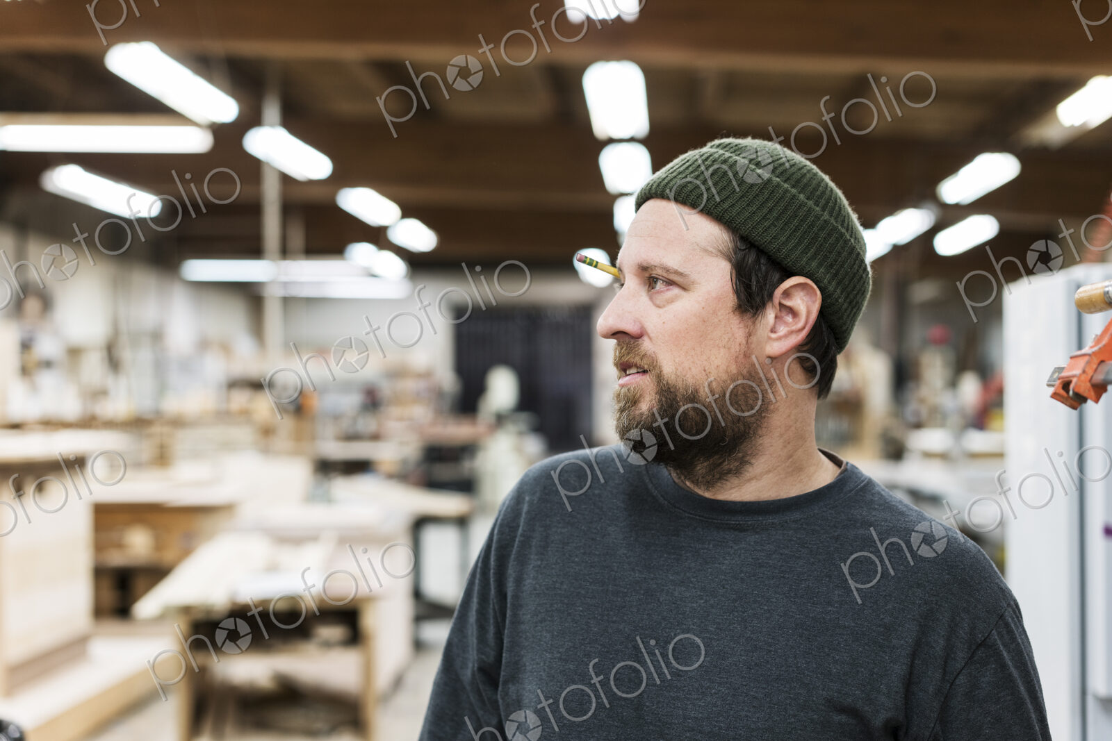 A portrait of a Caucasian carpenter working in a large woodworking shop.