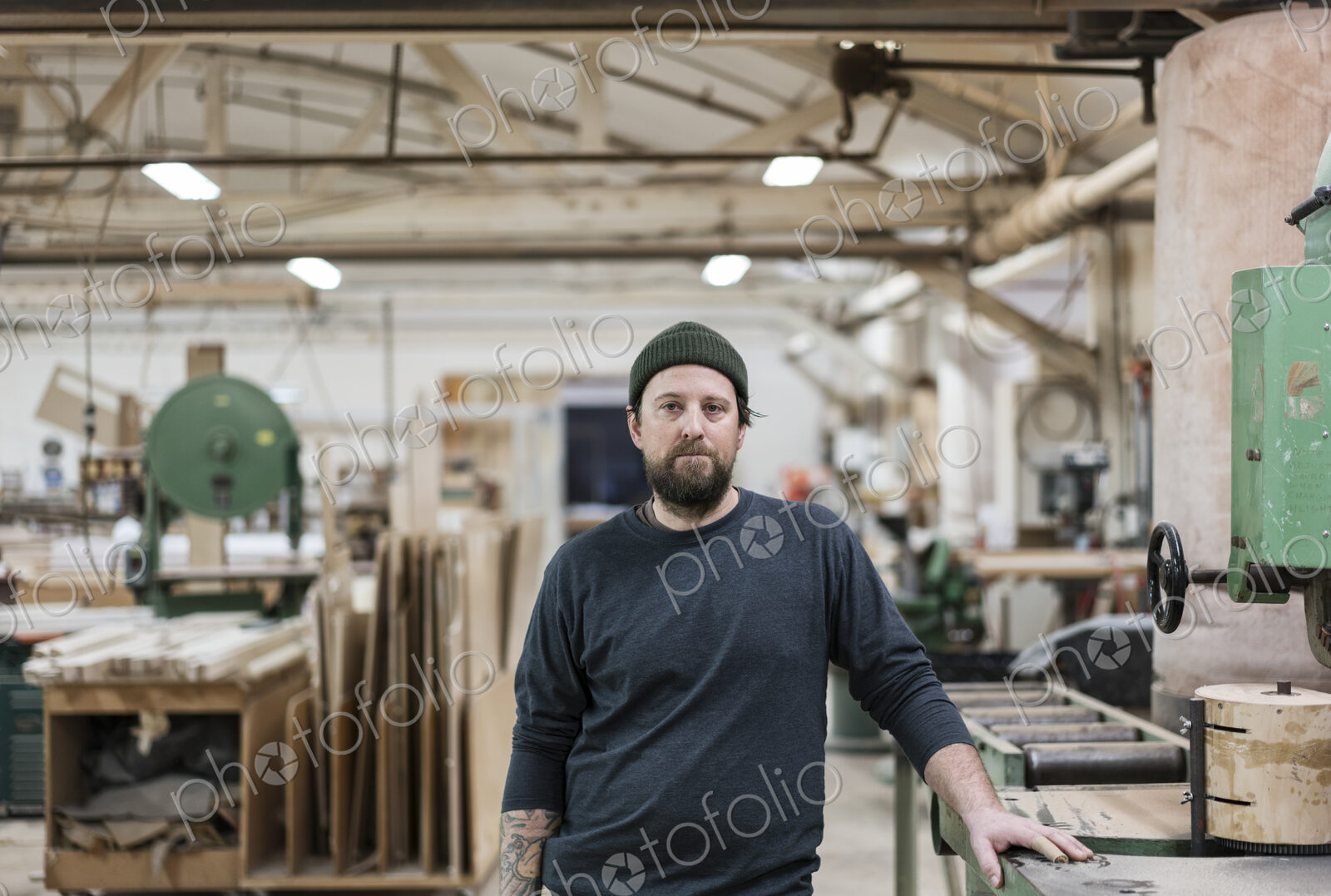 A portrait of a Caucasian carpenter working in a large woodworking shop.