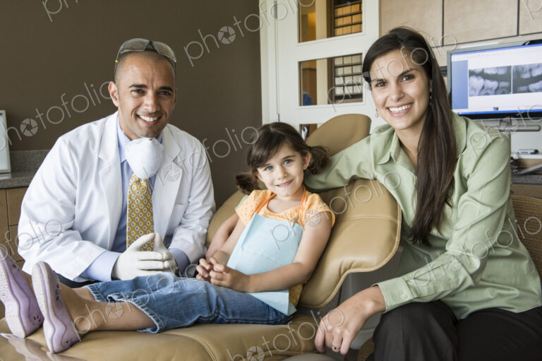 A portrait of a Middle Eastern male dentist a female child patient and her mom in a…