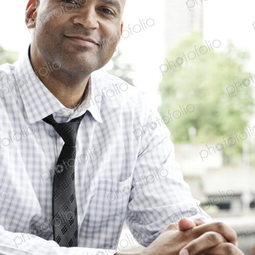 A portrait of a black businessman in a shirt and tie sitting at a desk next to a window. A portrait of a black businessman in a shirt and tie sitting at a desk next to a window.