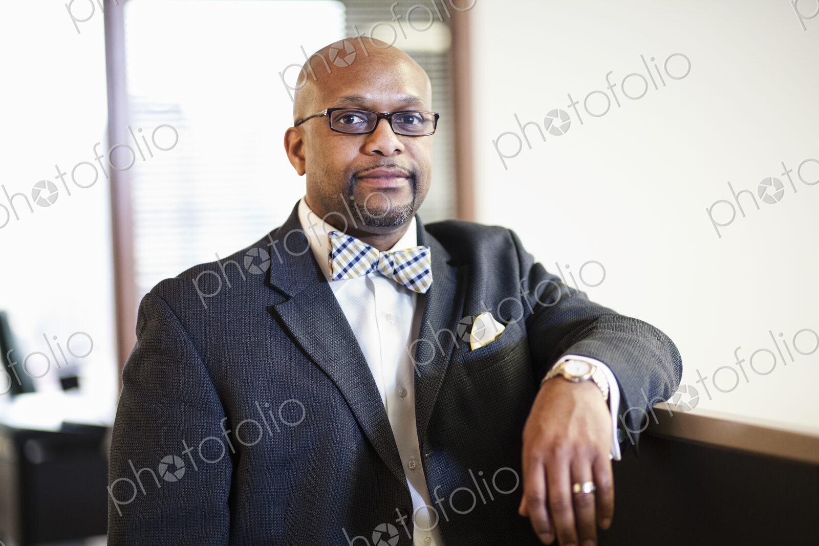 A portrait of a black businessman in a suit and bow tie.