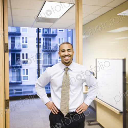 A portrait of a black businessman standing alone in his office space. A portrait of a black businessman standing alone in his office space.