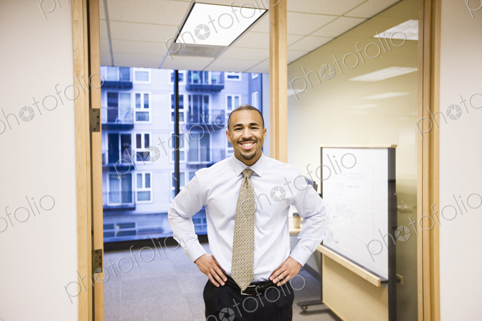 A portrait of a black businessman standing alone in his office space.