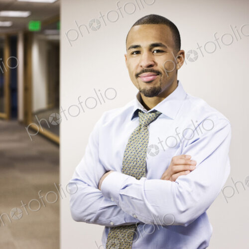 A portrait of a black businessman standing alone in his office space. A portrait of a black businessman standing alone in his office space.